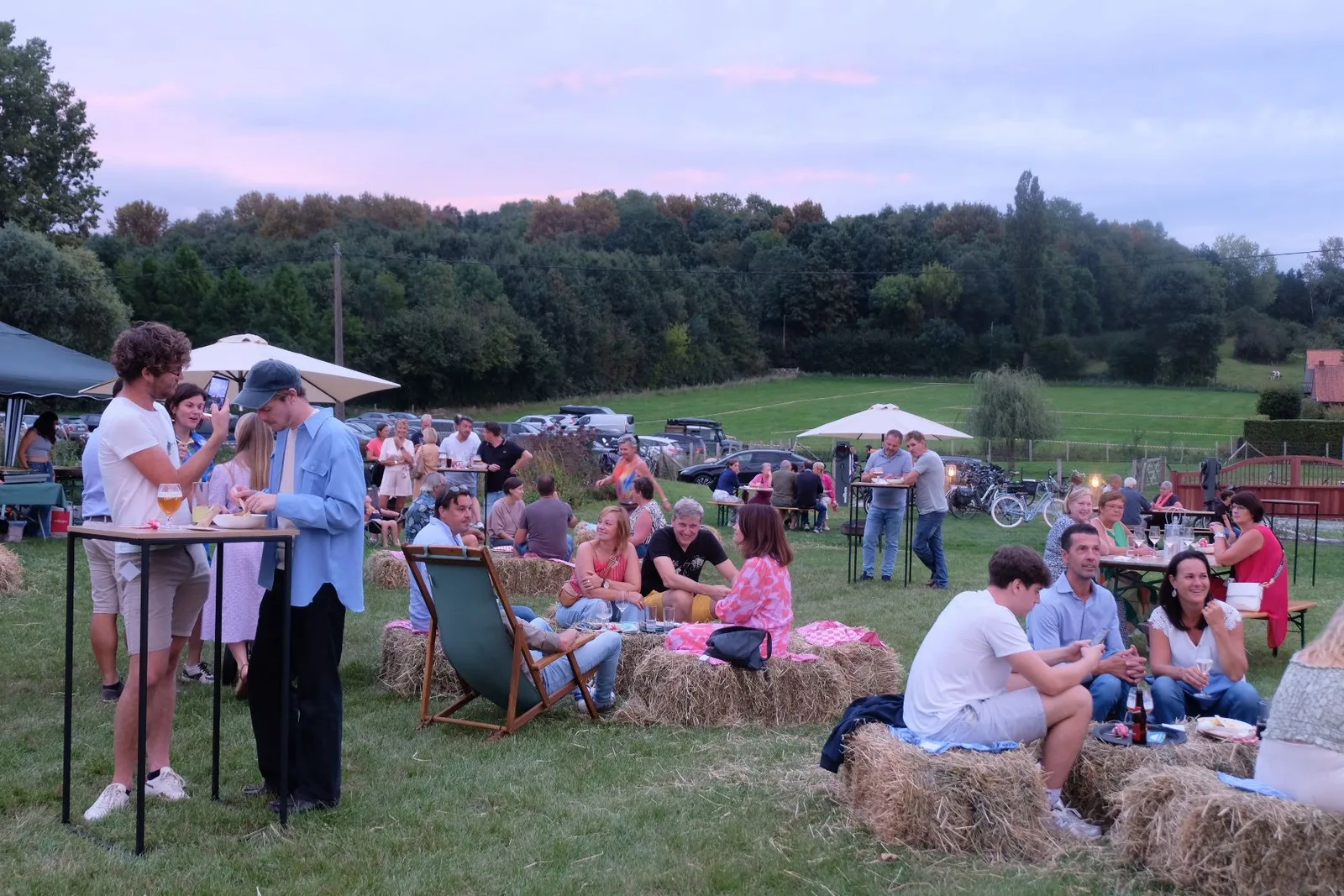 Zomeravondfeest op het grasplein met strobalen, statafels en parasols