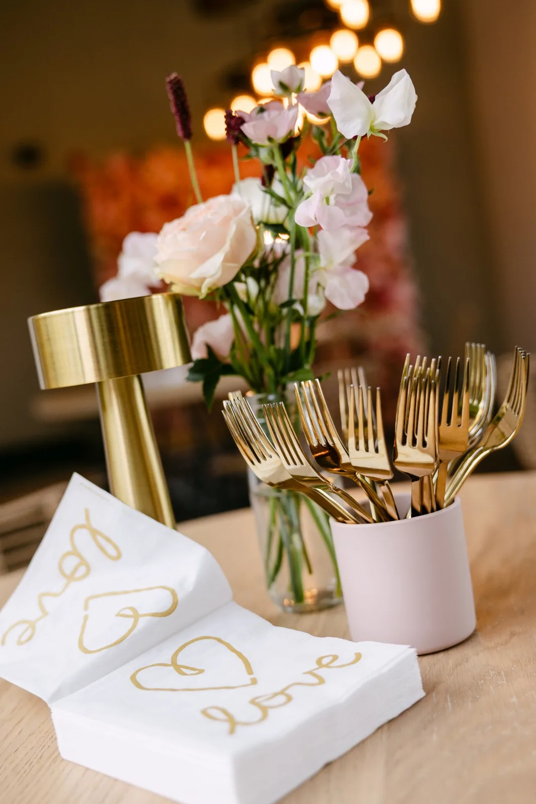 Tafeldetail met bloemen, gouden bestek en servetten met 'love'